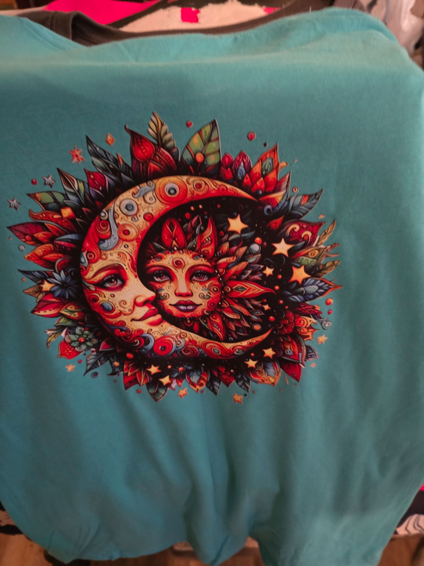 Back view showing large celestial sun and moon mandala design on aqua shirt